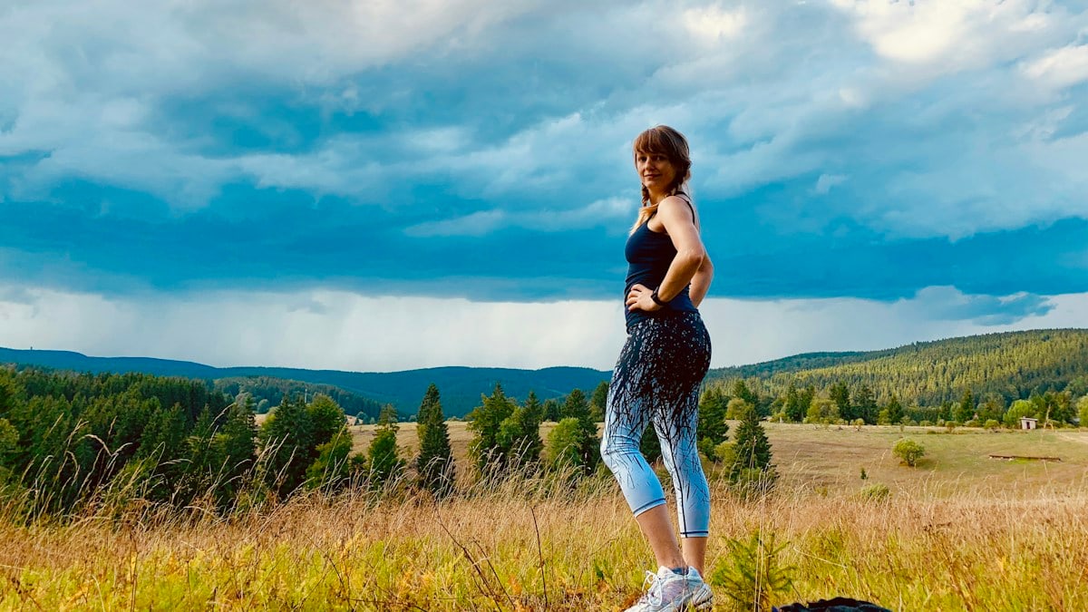 woman wearing black and teal ju7mp suit walking on grass field